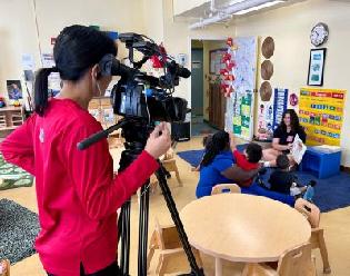 NBC4 Washington's Aimee Cho films Samantha reading to a group of preschoolers on a rug in the classroom.